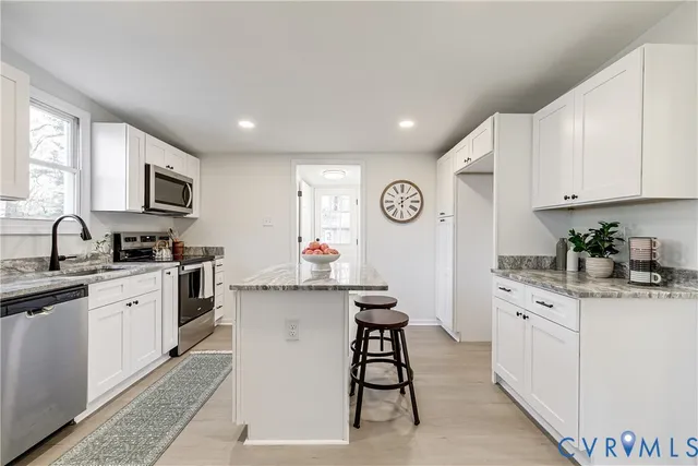 a kitchen with granite countertop a sink stove cabinets and window
