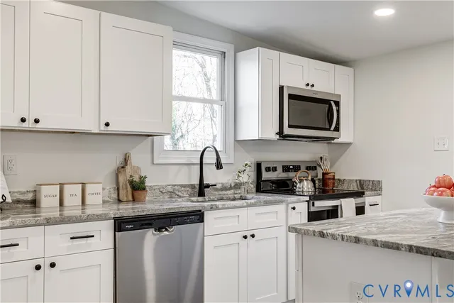 a kitchen with granite countertop white cabinets white appliances and a sink