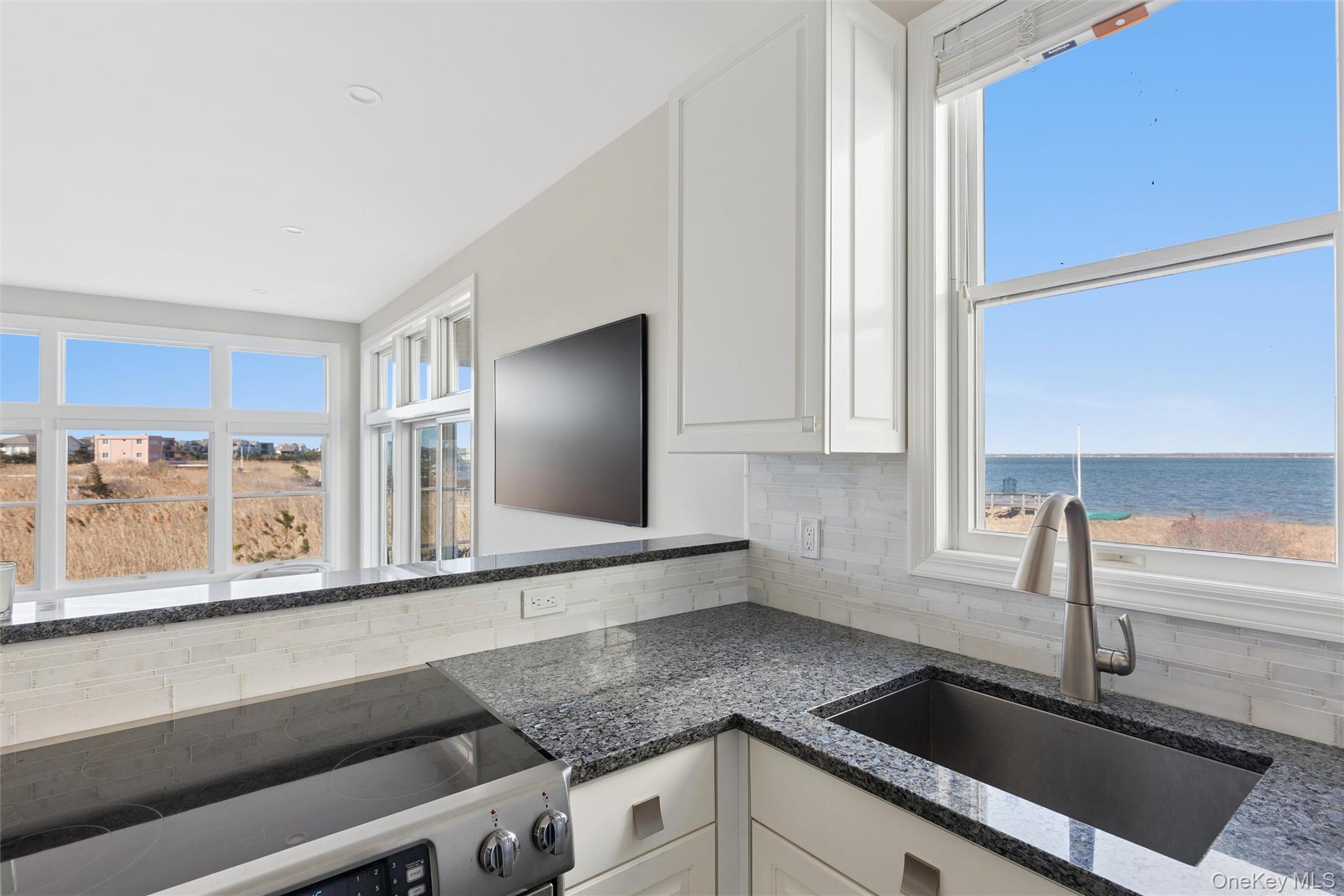 580 Dune Road, Unit 3 Westhampton Beach, NY 11978 - Photo 11 of 36 a kitchen with granite countertop a sink and a stove top oven
