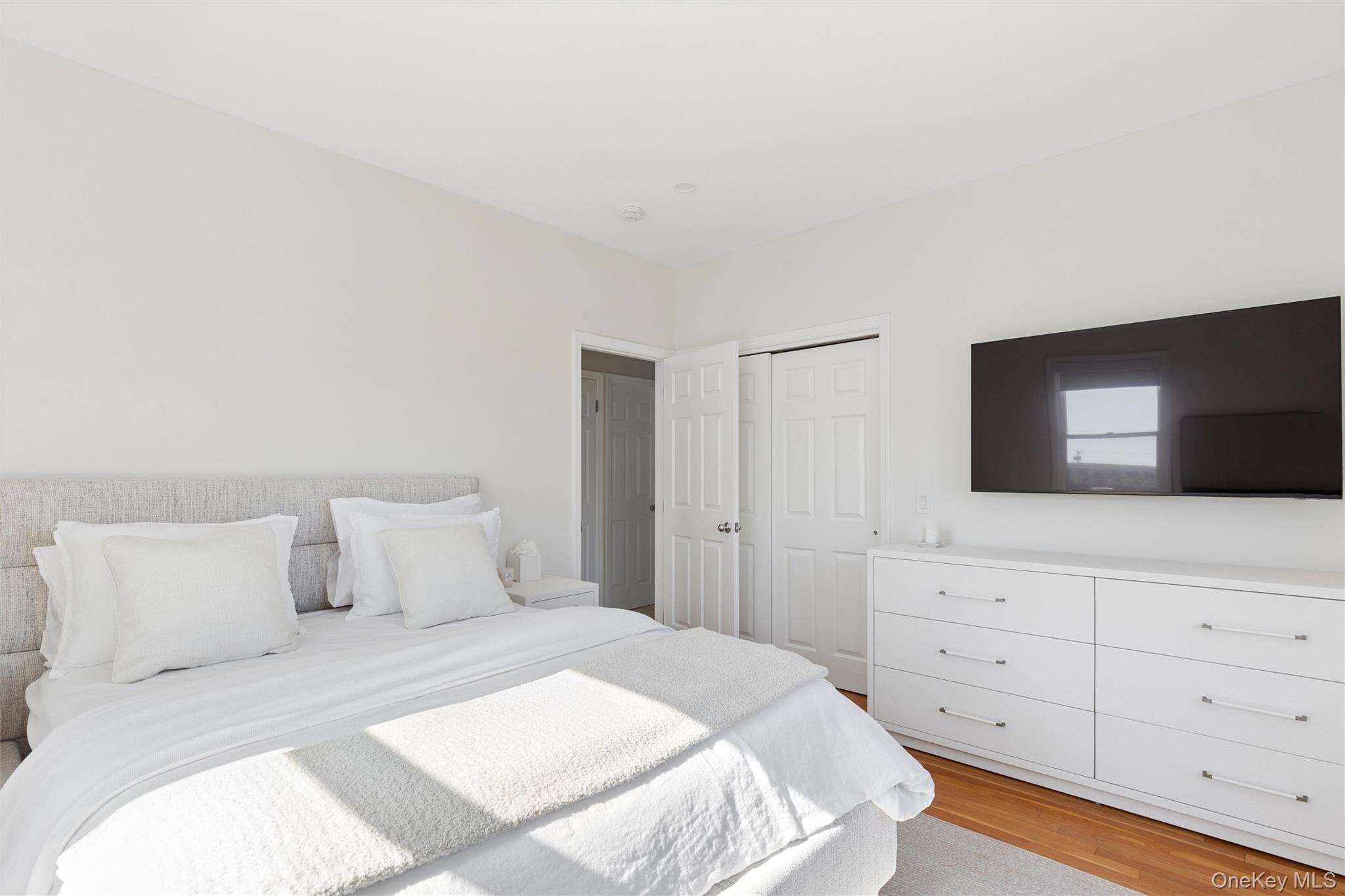 580 Dune Road, Unit 3 Westhampton Beach, NY 11978 - Photo 23 of 36 a bedroom with a bed and a flat screen tv