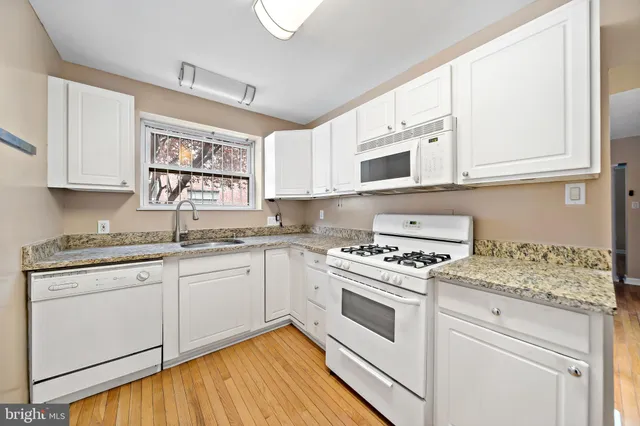 a kitchen with granite countertop white cabinets and white appliances