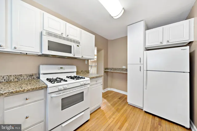 a kitchen with cabinets appliances wooden floor and a window
