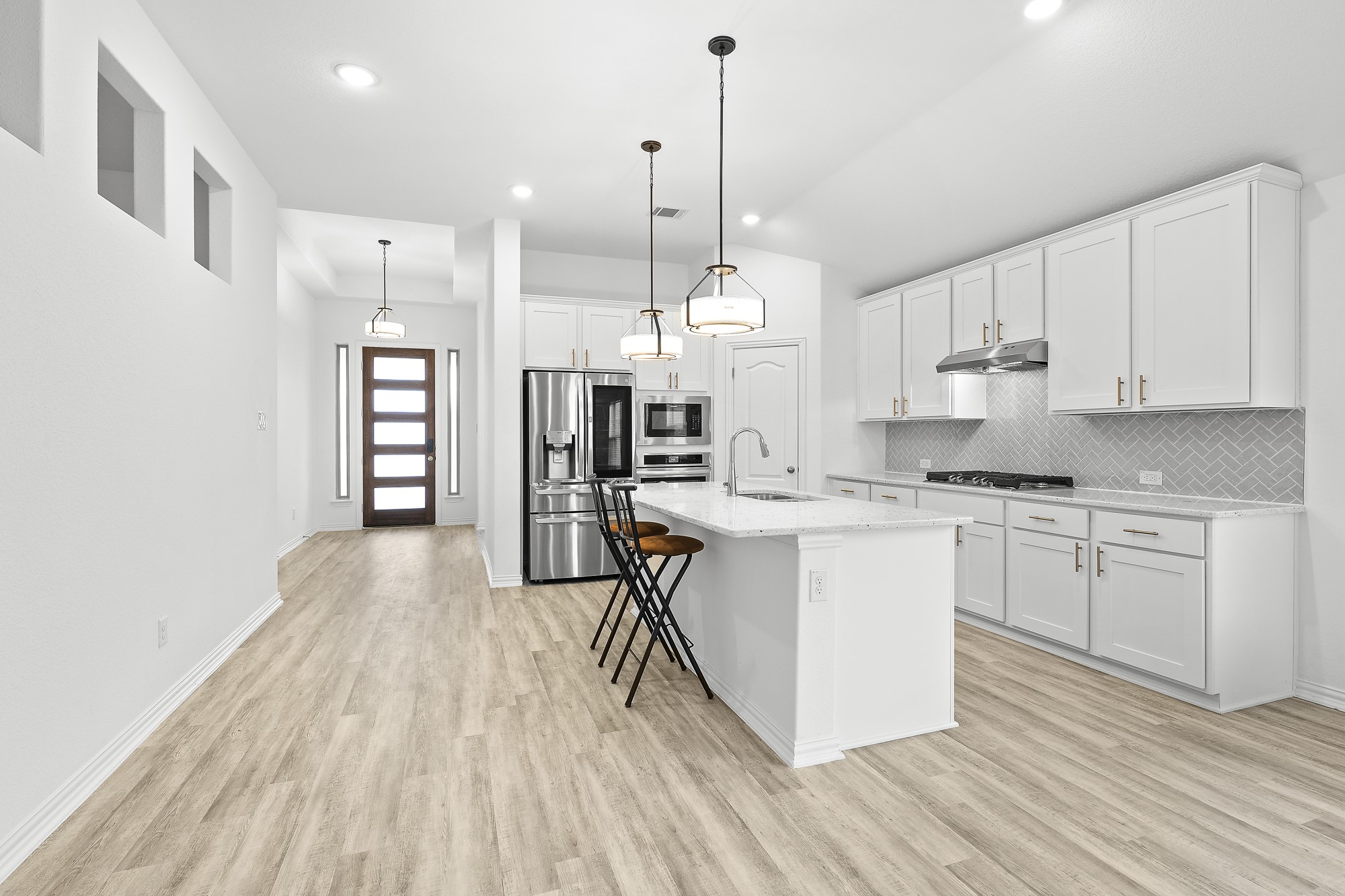 489 Cherrystone Loop Buda, TX 78610 - Photo 5 of 21 a kitchen with stainless steel appliances kitchen island granite countertop a refrigerator a stove a sink and white cabinets with wooden floor