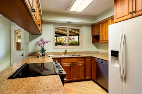 a kitchen with granite countertop a sink stove and refrigerator