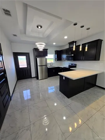 a large kitchen with stainless steel appliances a large counter top a stove a chimney a sink and a refrigerator