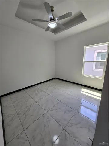 an empty room with windows and ceiling fan