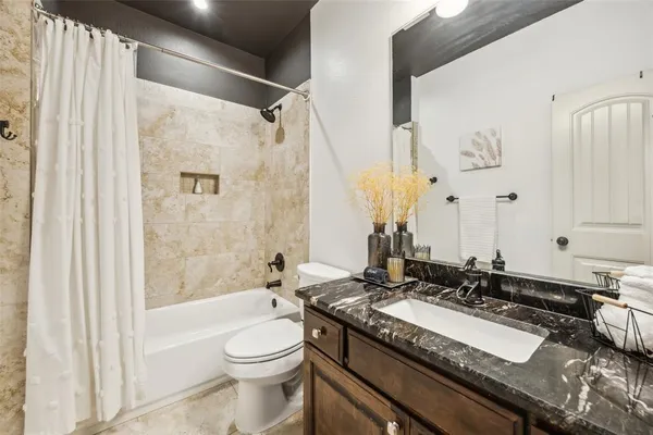 a bathroom with a granite countertop sink mirror vanity and a bathtub