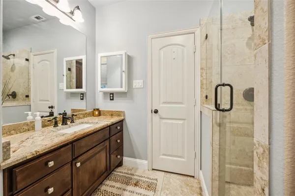 a spacious bathroom with a granite countertop sink two mirror and shower