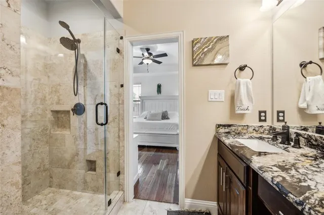 a bathroom with a granite countertop sink a mirror a shower and a mirror