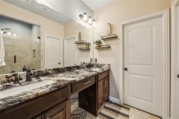 a bathroom with a granite countertop sink a mirror and a shower