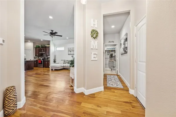 a view of a hallway with wooden floor and a bathroom