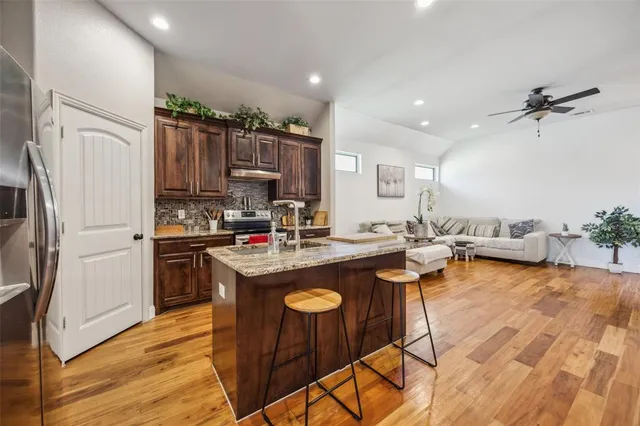 a kitchen with kitchen island granite countertop a sink refrigerator and cabinets