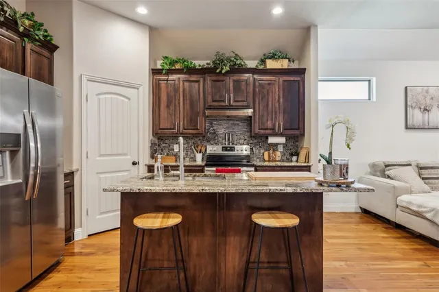 a kitchen with granite countertop a sink refrigerator and cabinets