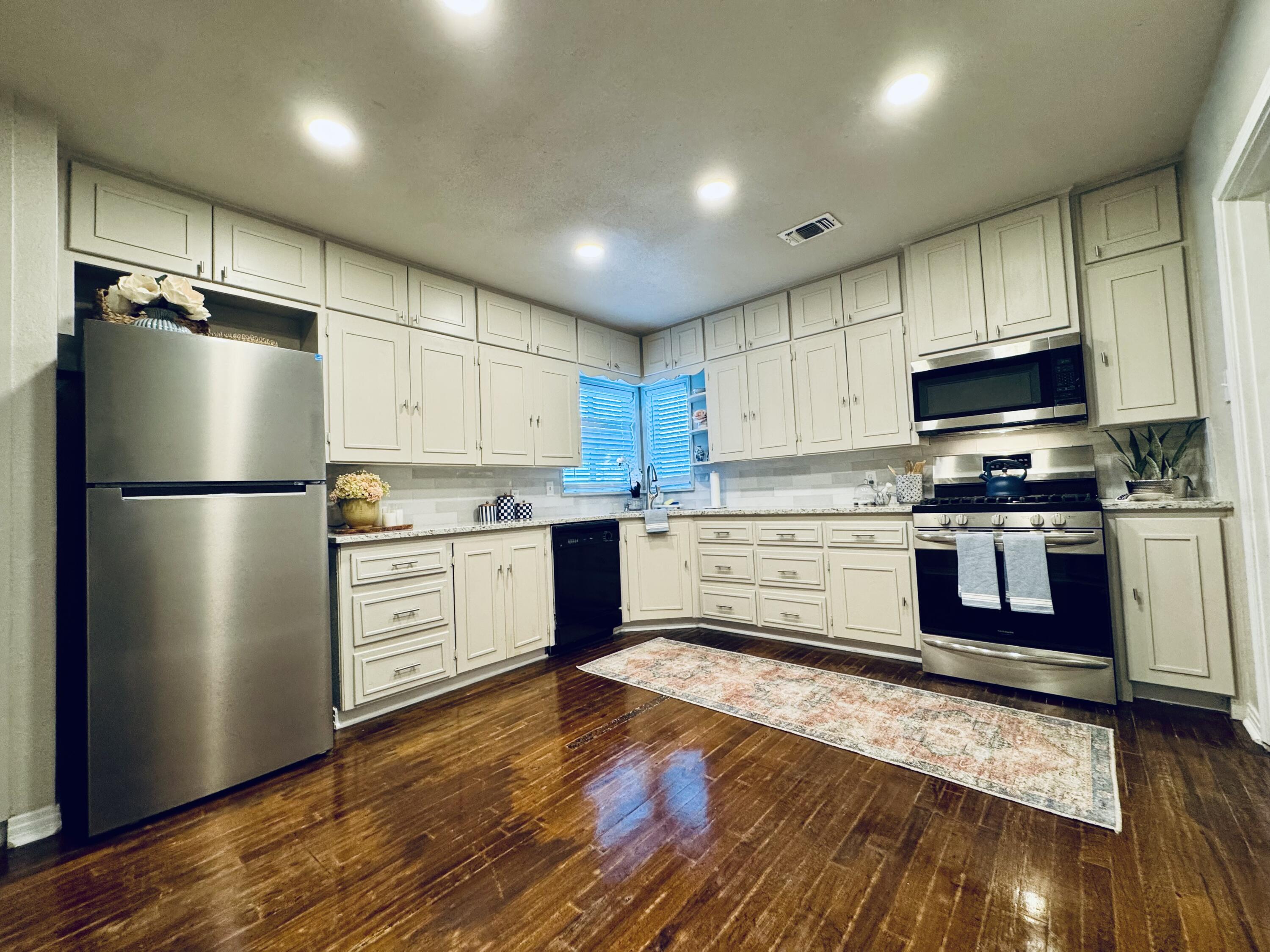 a kitchen with granite countertop a refrigerator stove and wooden cabinets