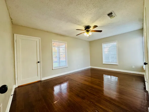 a view of empty room with wooden floor and fan