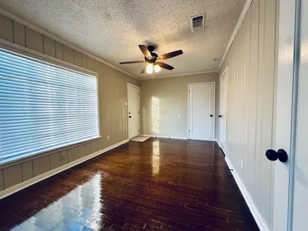 a view of an empty room with a window and wooden floor