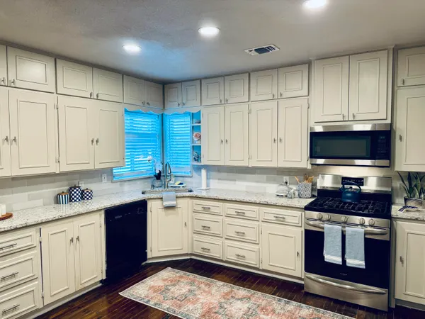 a kitchen with stainless steel appliances granite countertop a stove a sink and a microwave