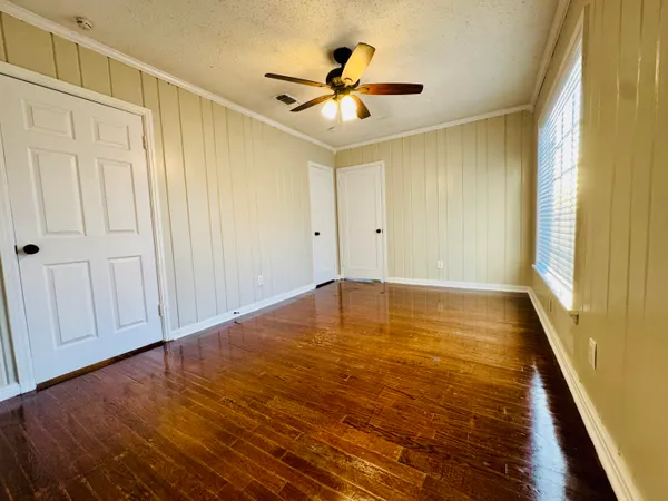 a view of empty room with wooden floor and fan