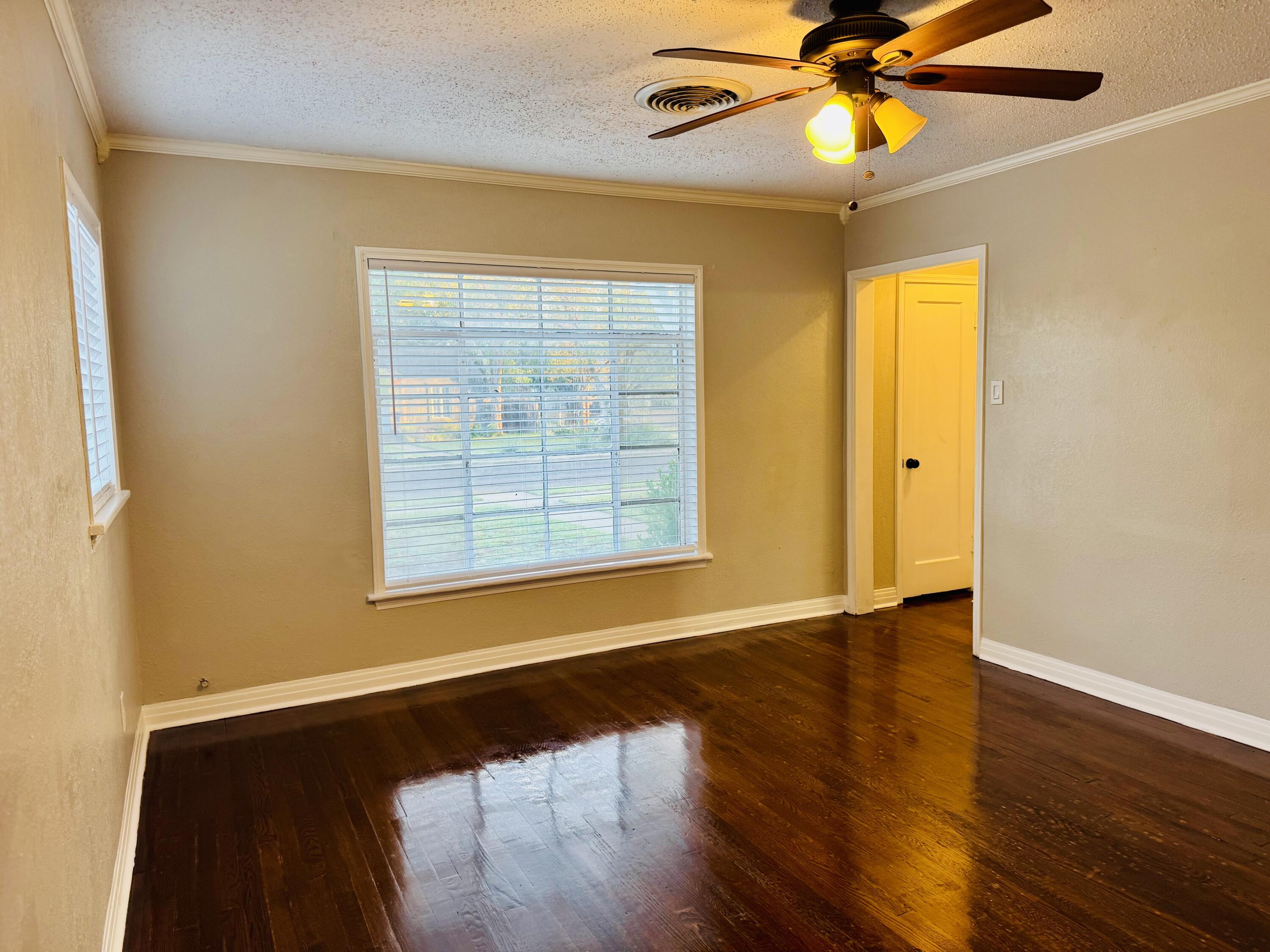 2509 30th Street Lubbock, TX 79410 - Photo 9 of 26 a view of an empty room with wooden floor and a window