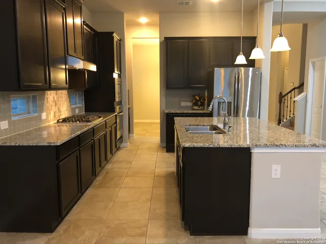 a kitchen with stainless steel appliances granite countertop a sink and a refrigerator