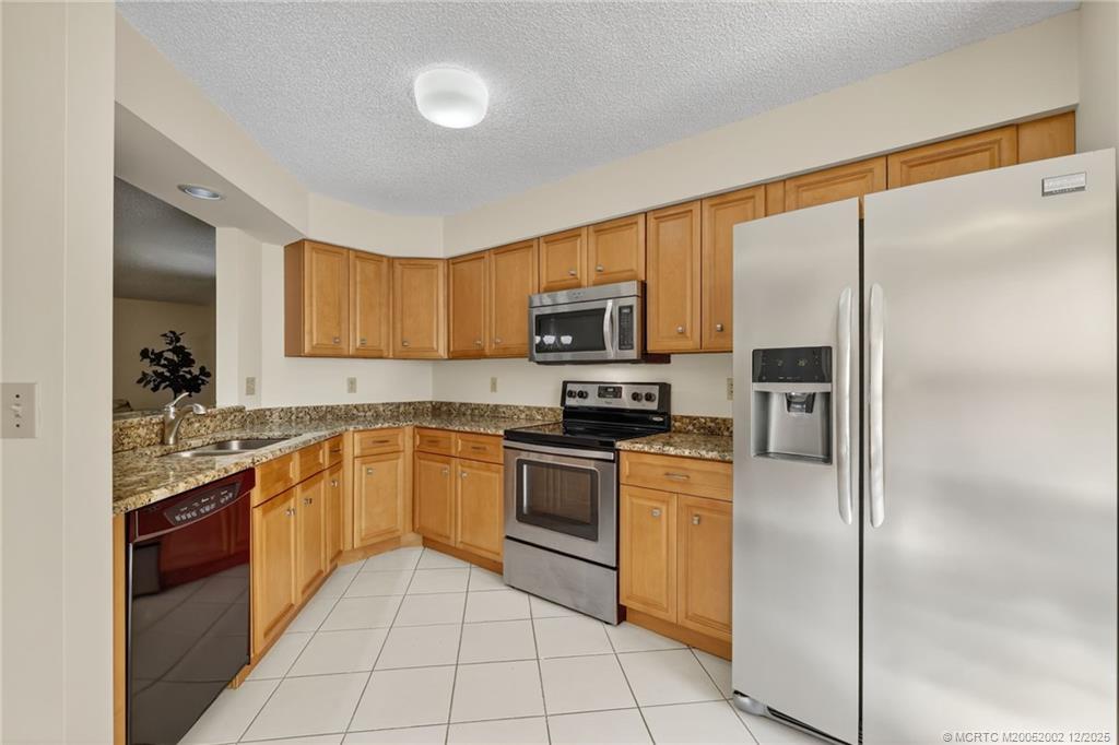 3460 Southeast Martinique Trace, Unit 103 Stuart, FL 34997 - Photo 11 of 42 a kitchen with stainless steel appliances granite countertop a refrigerator and a stove top oven