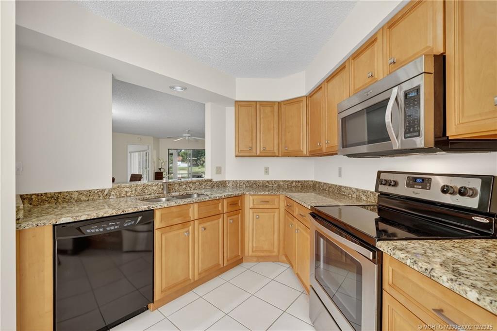 3460 Southeast Martinique Trace, Unit 103 Stuart, FL 34997 - Photo 12 of 42 a kitchen with stainless steel appliances granite countertop a stove sink and cabinets