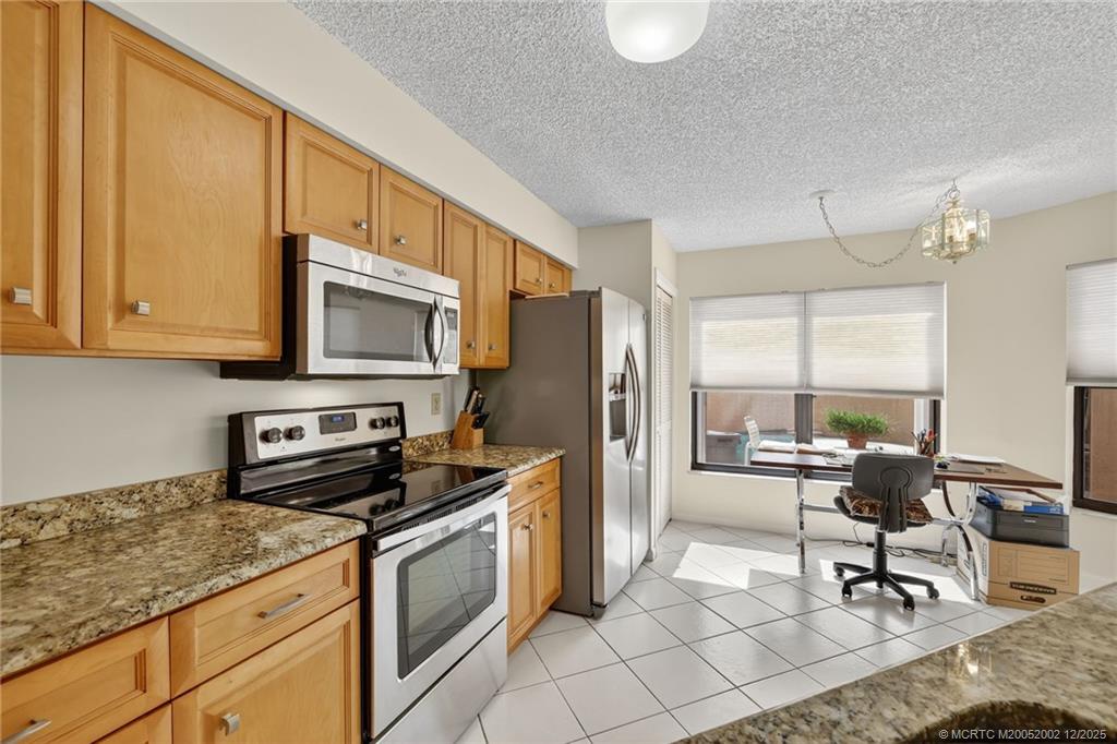 3460 Southeast Martinique Trace, Unit 103 Stuart, FL 34997 - Photo 13 of 42 a kitchen with stainless steel appliances granite countertop a stove a sink dishwasher and a refrigerator with wooden cabinets