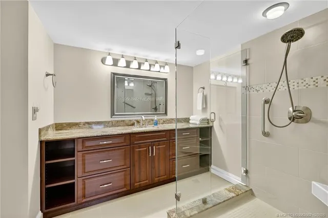 a spacious bathroom with a granite countertop sink a mirror and a shower