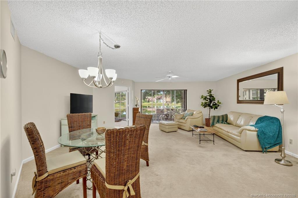 3460 Southeast Martinique Trace, Unit 103 Stuart, FL 34997 - Photo 6 of 42 a living room with furniture chandelier and a fireplace