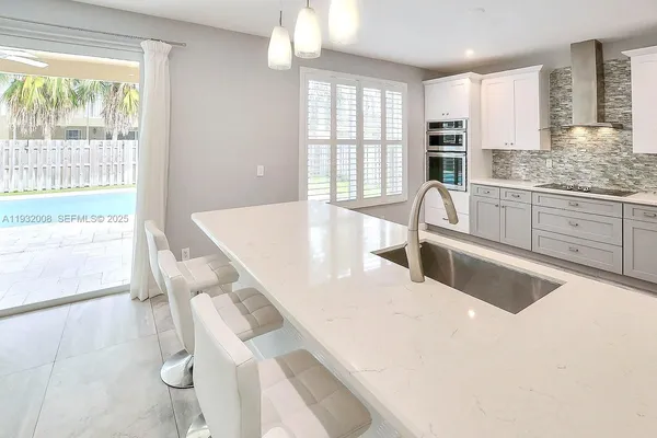 a large white kitchen with large windows and refrigerator