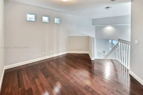 a view of an empty room with wooden floor and a window
