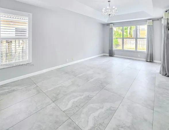 an empty room with windows and chandelier fan
