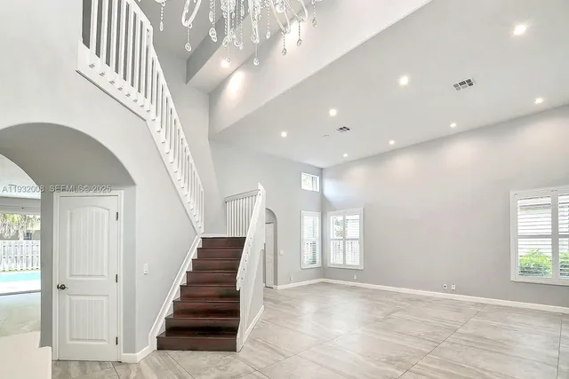 a view of a kitchen with kitchen island a large window cabinets a sink and a counter top space