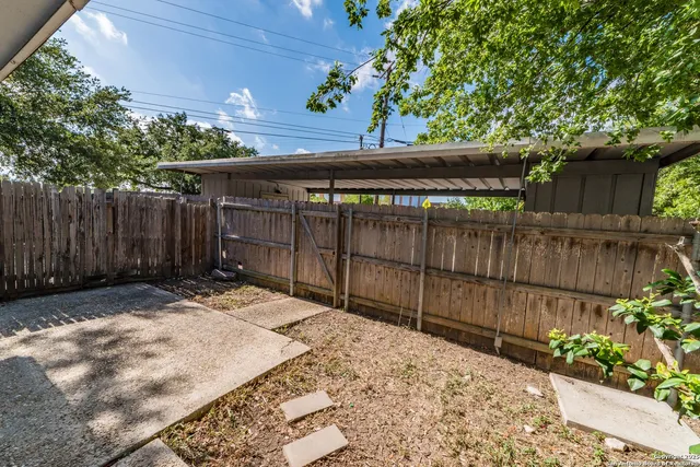 a wooden fence and trees in the back yard