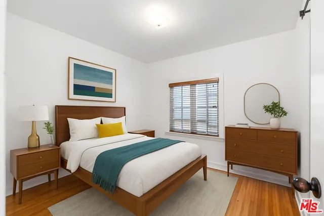 a bedroom with a bed a dresser and windows