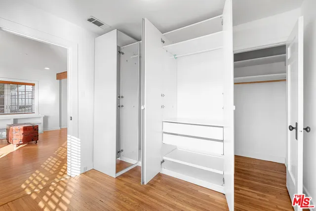 a view of walk in closet with hardwood floor and a bathroom