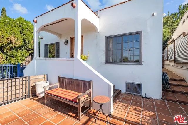 a balcony with couple of chairs and a potted plant