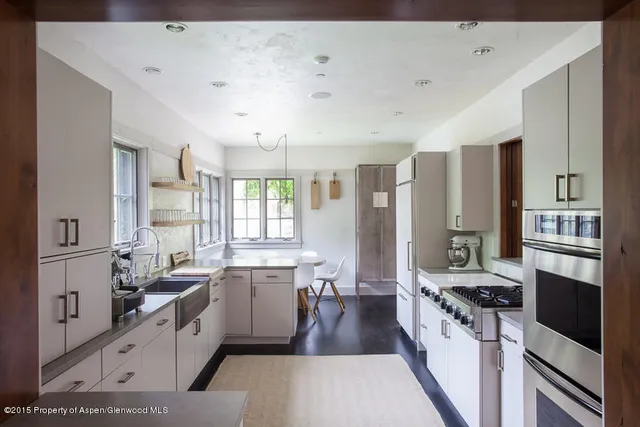 a large white kitchen with a large window and stainless steel appliances