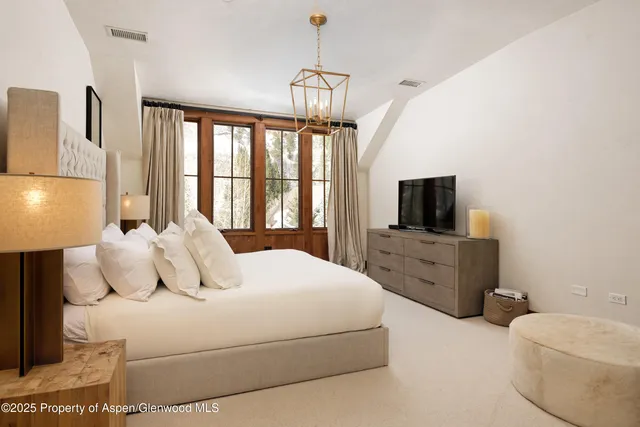 a bedroom with a bed flat screen tv and a window