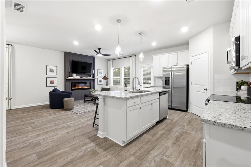 3227 Winding Waters Way, Unit 36 Powder Springs, GA 30127 - Photo 8 of 30 a kitchen with stainless steel appliances kitchen island granite countertop a stove a sink a refrigerator and a microwave