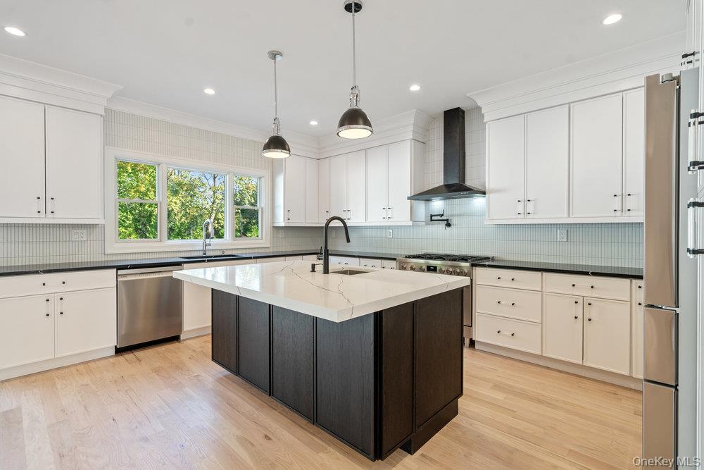 47 Netz Place Albertson, NY 11507 - Photo 11 of 41 Kitchen with wall chimney exhaust hood, ornamental molding, appliances with stainless steel finishes, light wood-style floors, and decorative backsplash
