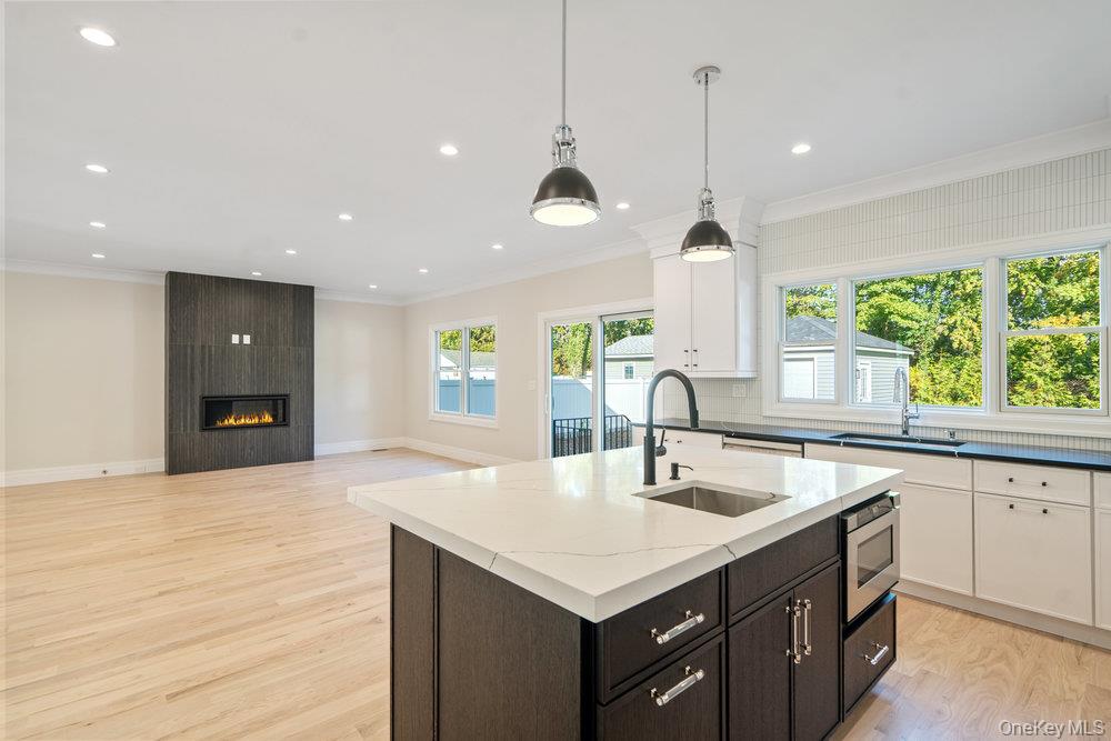 47 Netz Place Albertson, NY 11507 - Photo 37 of 41 Kitchen with crown molding, open floor plan, an island with sink, white cabinetry, and decorative light fixtures