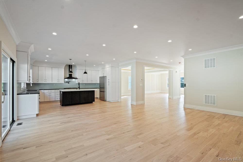 47 Netz Place Albertson, NY 11507 - Photo 39 of 41 Kitchen featuring open floor plan, ornamental molding, an island with sink, white cabinets, and light wood-style floors