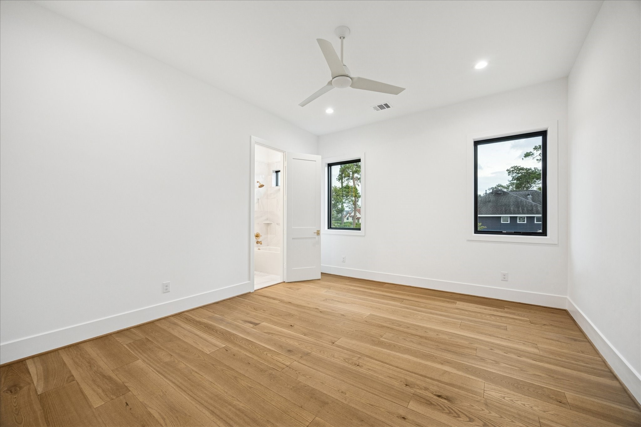 830 Azalea Street Houston, TX 77018 - Photo 28 of 50 A calm, neutral palette and large windows define this secondary bedroom, complete with its own en-suite bath for a streamlined, functional layout.