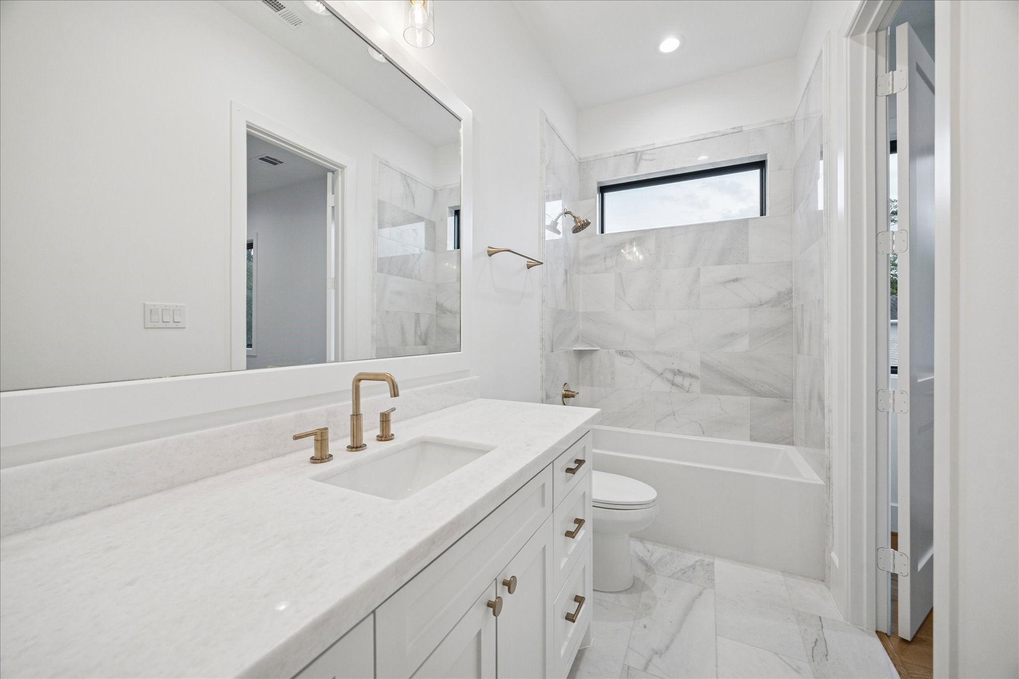 830 Azalea Street Houston, TX 77018 - Photo 29 of 50 Soft neutral tones, polished tile, and warm brass accents create a refined, modern atmosphere in this secondary en-suite bath.