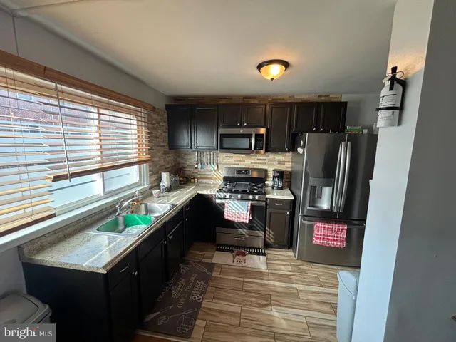 a kitchen with granite countertop a refrigerator stove and sink