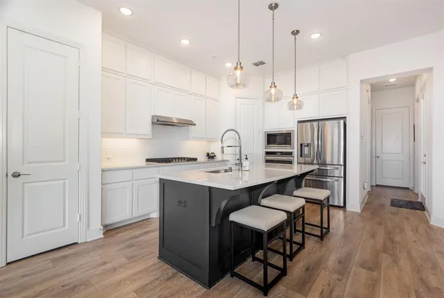 a kitchen with kitchen island granite countertop a sink cabinets and wooden floor