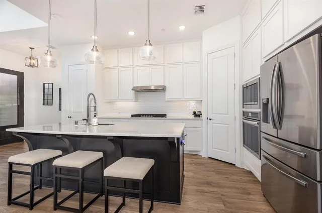 a kitchen with kitchen island granite countertop a sink cabinets and stainless steel appliances