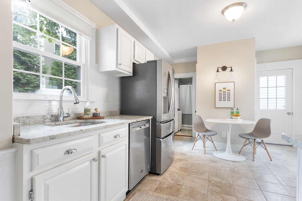 170 West Street, Unit 170 Needham, MA 02494 - Photo 10 of 32 a kitchen with stainless steel appliances kitchen island granite countertop a table and chairs in it
