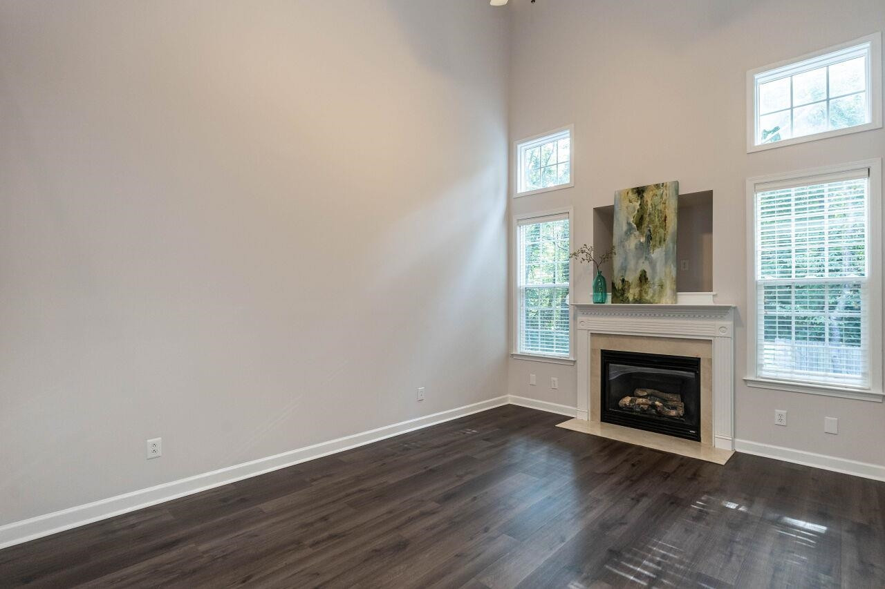 5948 Kohler Lane Raleigh, NC 27616 - Photo 13 of 32 an empty room with wooden floor fireplace and windows